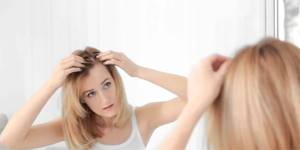 Young woman checking hairline thinning in mirror, exploring hair transplant for women procedures